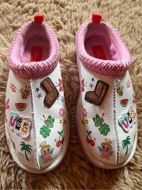UGG Kids White Slip-On Shoes with Pink Trim and Colorful Sticker Prints